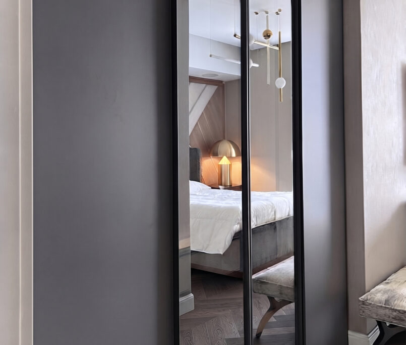 Bespoke Italian fitted wardrobe featuring matte grey lacquer panels and full-height mirrored sliding doors in a luxury bedroom