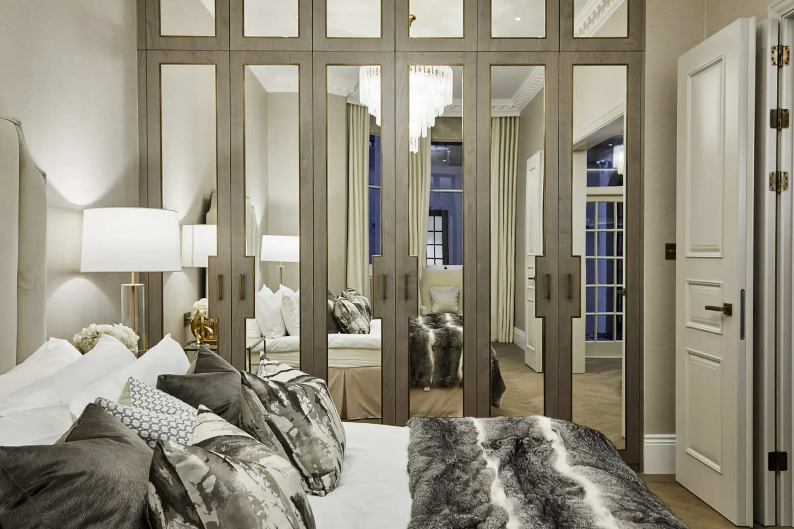 Bespoke floor-to-ceiling mirrored wardrobe joinery with bronze handles in a luxury London master bedroom by Paolo Rota Interiors