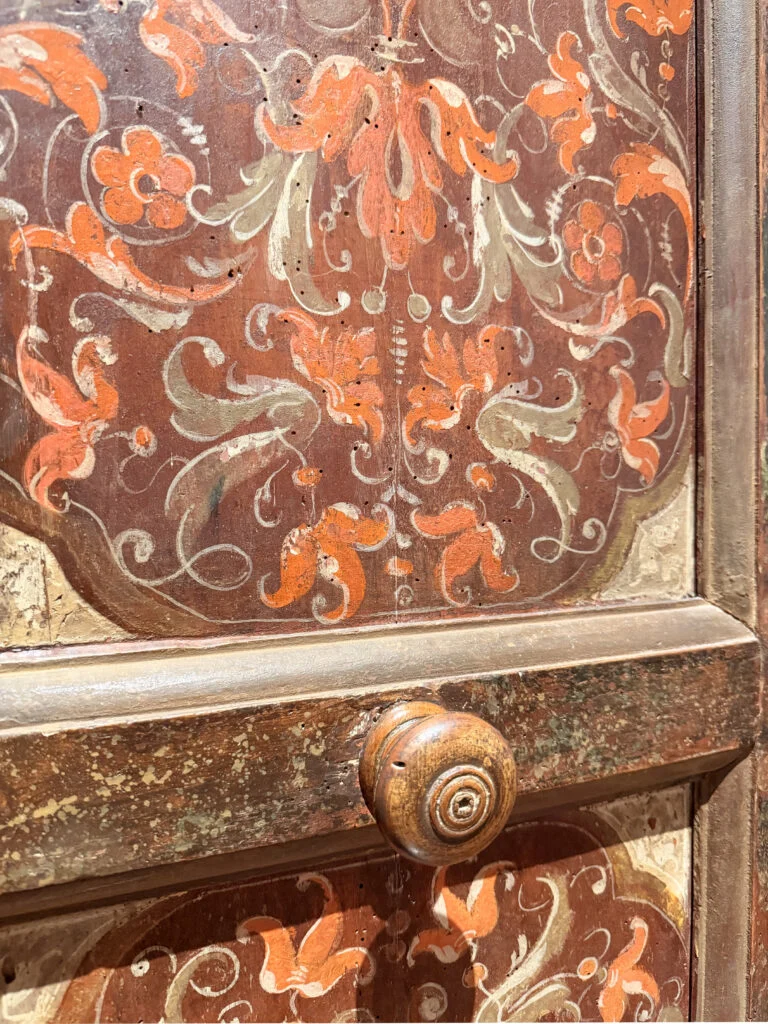 Close-up of a hand-painted Renaissance wardrobe door and wooden knob in Gubbio, inspiring custom joinery for an Italian interior designer in London and Milan