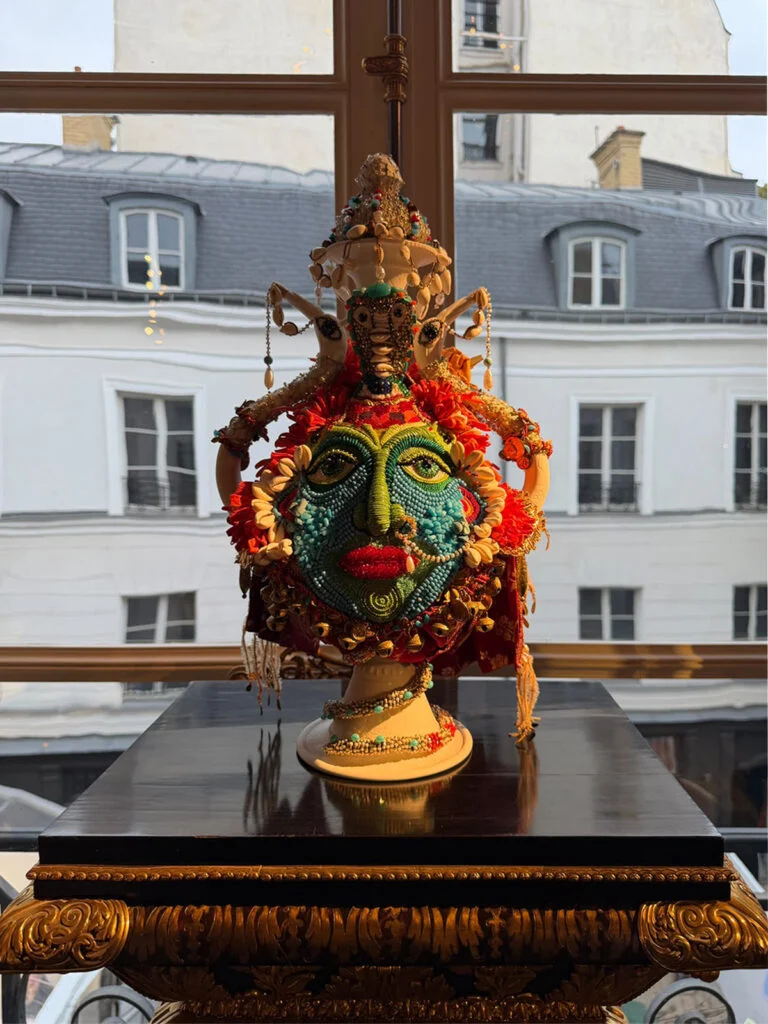 Ornate handcrafted beaded and ceramic anthropomorphic sculptural vessel set against a Parisian courtyard window at Design Miami Paris