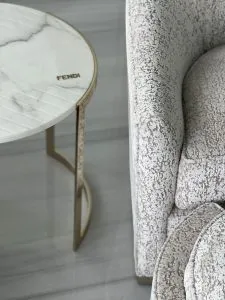 Fendi marble side table with brass frame beside a textured upholstered sofa, luxury furniture procurement by Paolo Rota Interiors in London