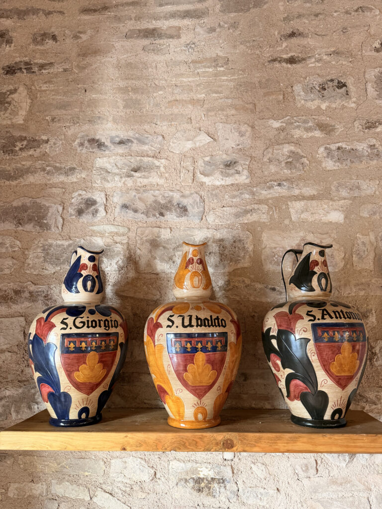 Handcrafted ceramic vessels with heraldic crests on display at MUAM Gubbio, curated by an Italian interior designer