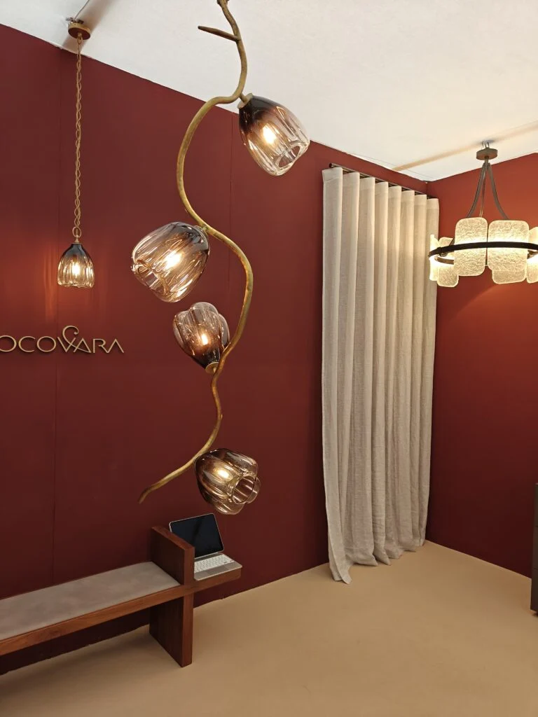 Cococovara bespoke sculptural brass vine chandelier with smoked fluted glass shades against terracotta wall at Decorex London