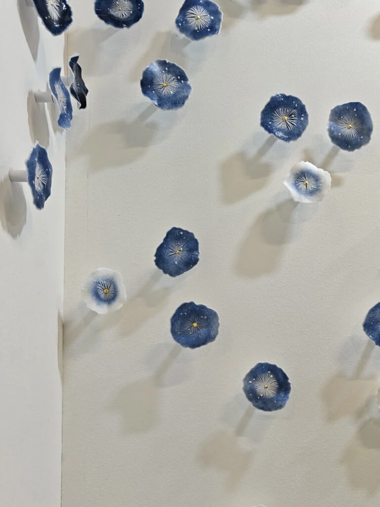 Handcrafted cobalt blue and white porcelain floral wall sculpture installation at Decorex London